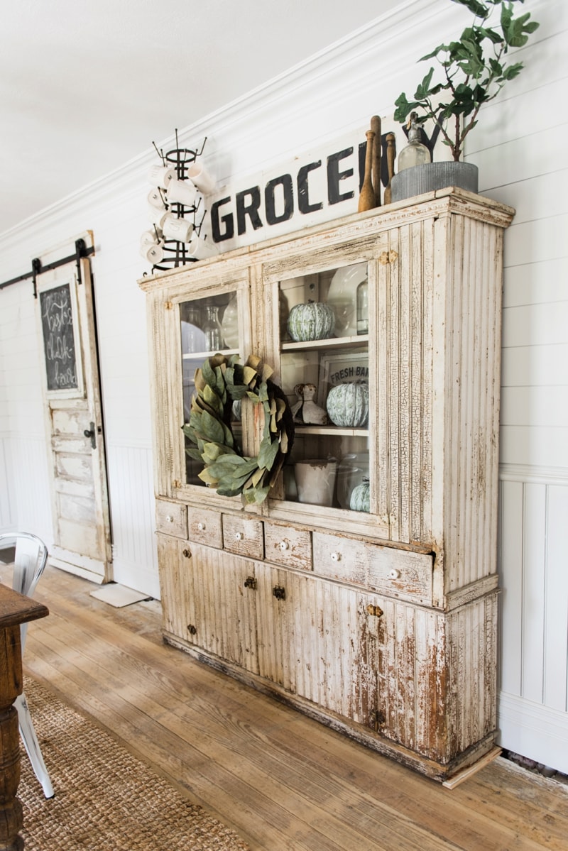 Primitive dining room hutch. Neutral farmhouse dining room. Shiplap walls, primitive furniture, magnolia wreaths, & so much more. Great pin for cottage style/farmhouse style inspiration. 