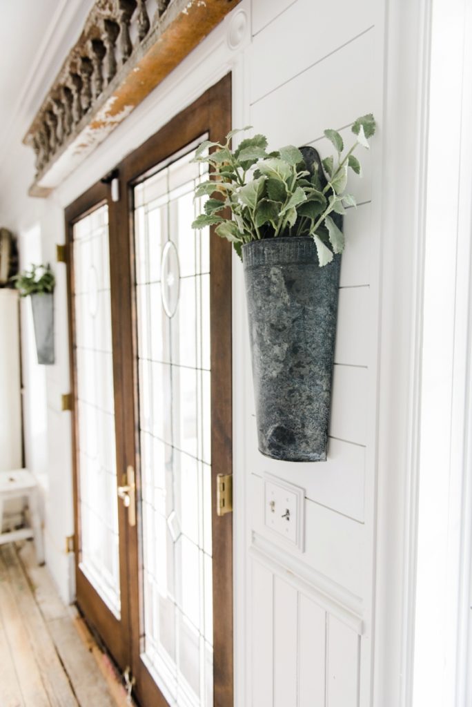 Hanging metal vases with flowers hanging on each side of the french doors. Great farmhouse decor style tips & tricks. A must pin for cottage style and farmhouse style decor. Metal flower vases from Magnolia Market 