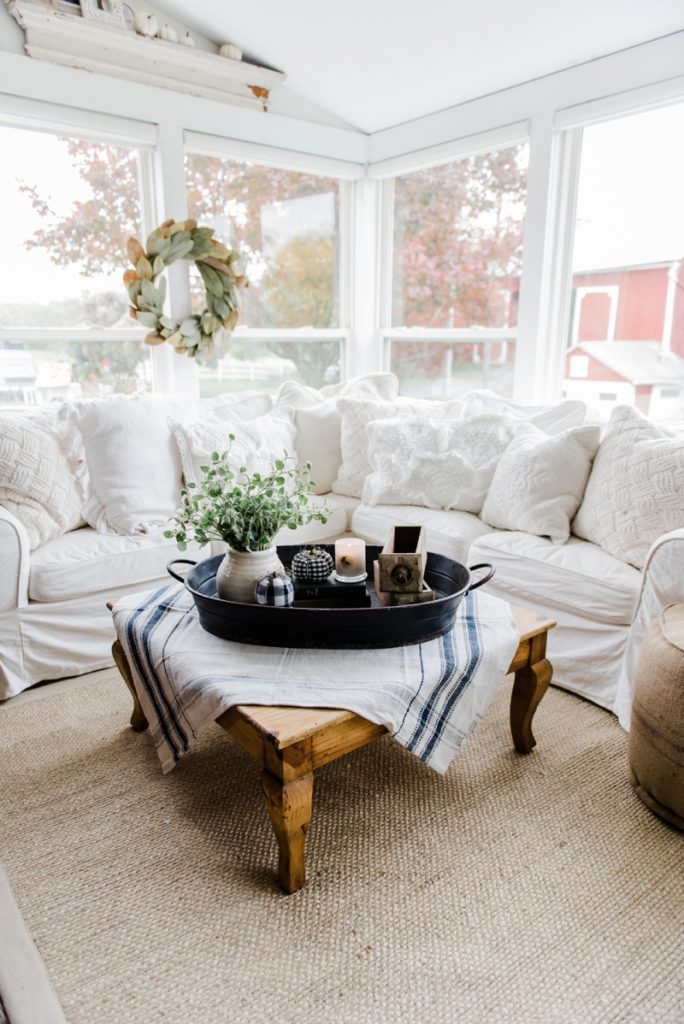 Farmhouse style coffee table in the sunroom - A lovely warm wood style coffee table style with a tablecloth on top to cozy it up. A great source for farmhouse & cottage style home decor!