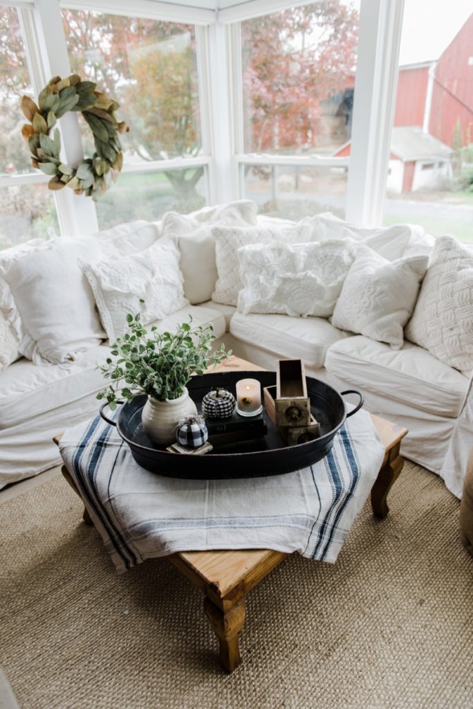 Farmhouse style coffee table in the sunroom - A lovely warm wood style coffee table style with a tablecloth on top to cozy it up. A great source for farmhouse & cottage style home decor!