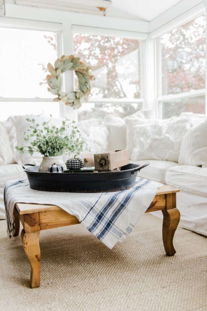 Farmhouse style coffee table in the sunroom - A lovely warm wood style coffee table style with a tablecloth on top to cozy it up. A great source for farmhouse & cottage style home decor!