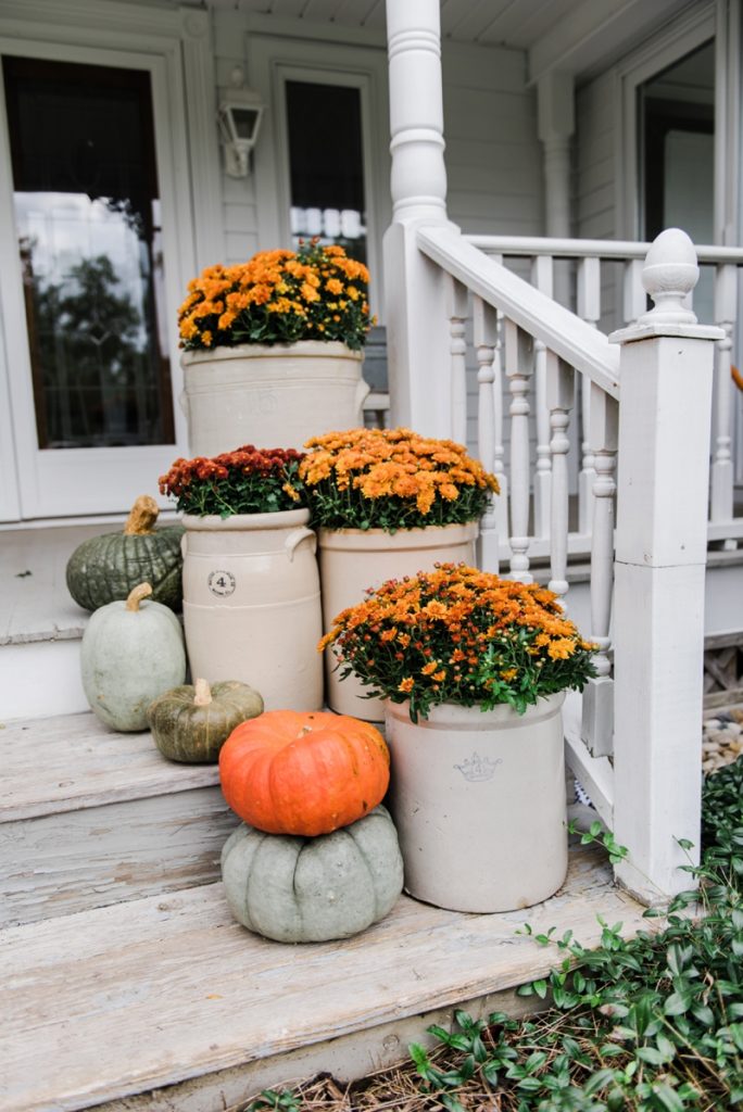 Cozy Rustic Fall porch - Mums in crocks to give a farmhouse porch an instant fall vibe. Great source for farmhouse decor. 