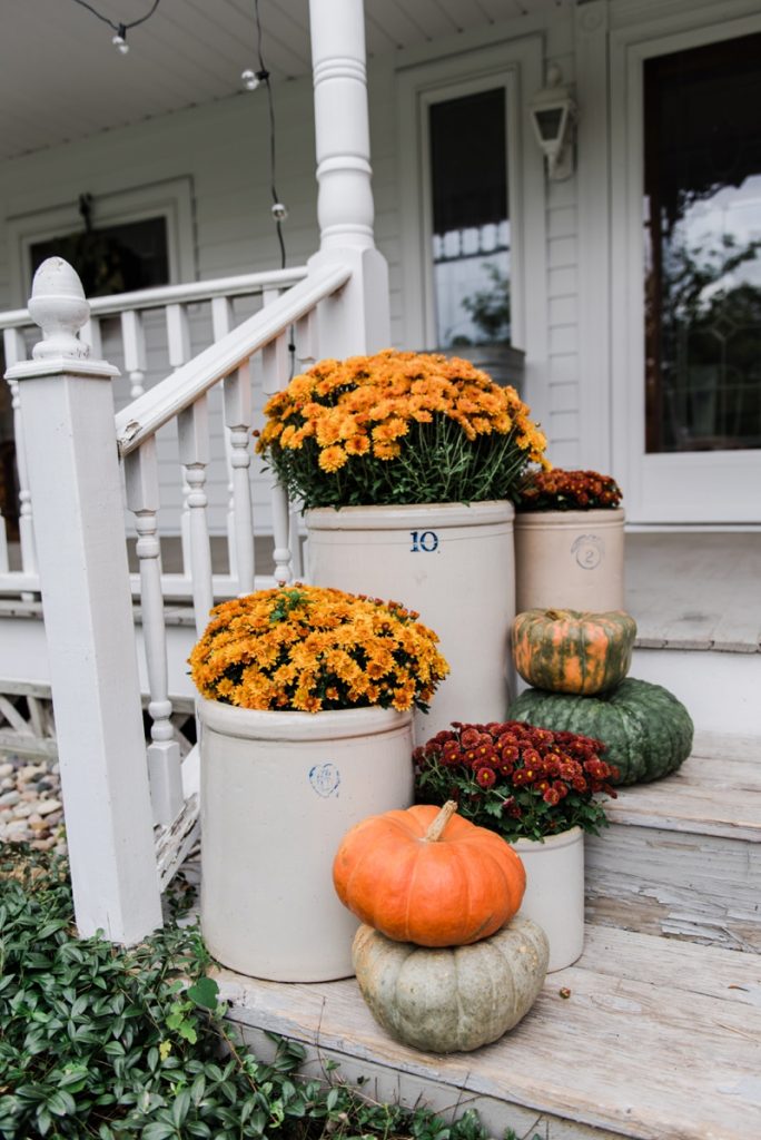 Cozy Rustic Fall porch - Mums in crocks to give a farmhouse porch an instant fall vibe. Great source for farmhouse decor. 