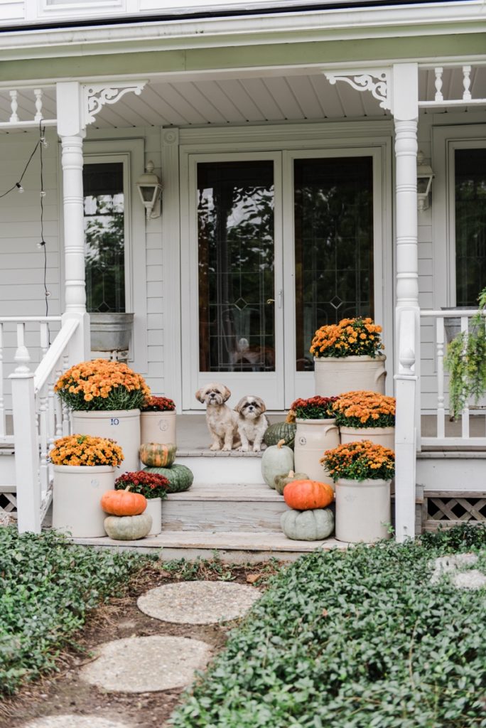 Cozy Rustic Fall porch - Mums in crocks to give a farmhouse porch an instant fall vibe. Great source for farmhouse decor. 