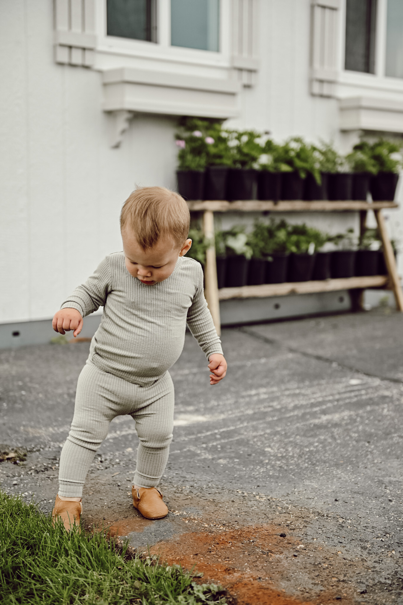 Little Boy stepping off patio with plants in the background 